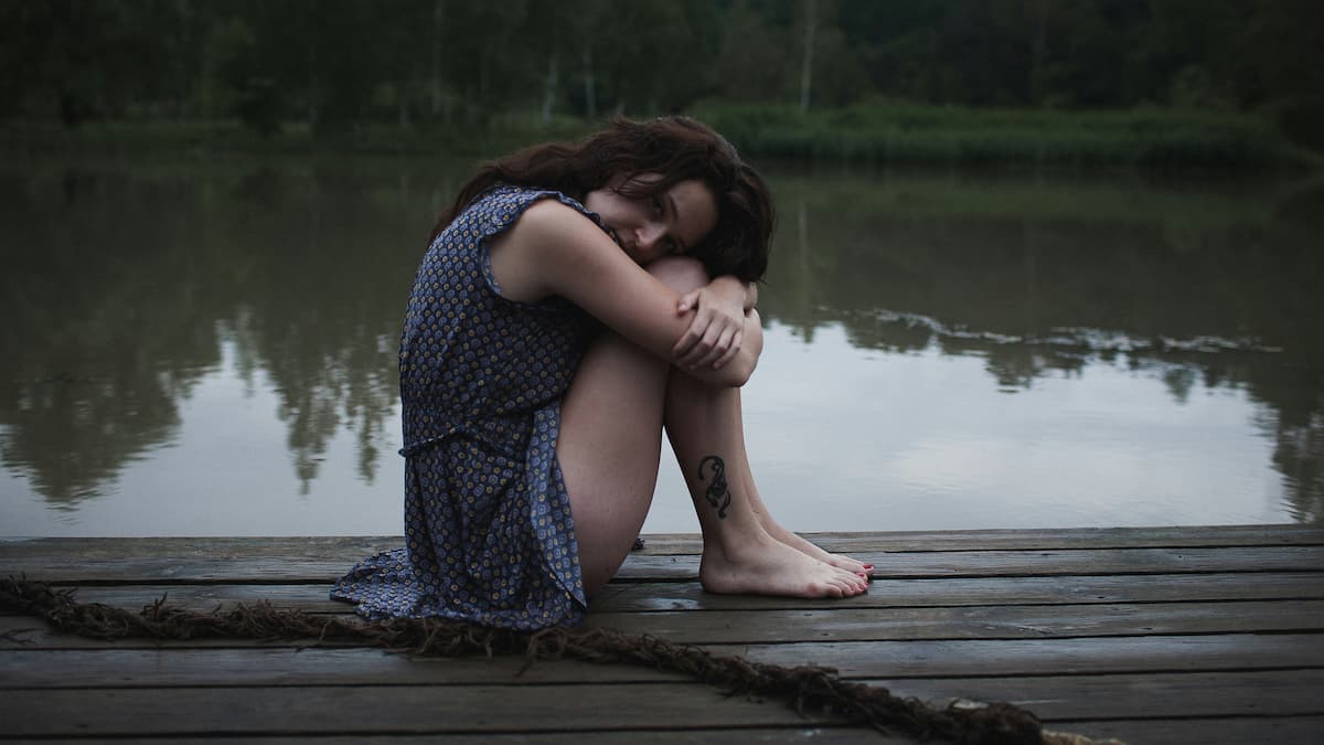 Woman sitting on dock, sad after break up