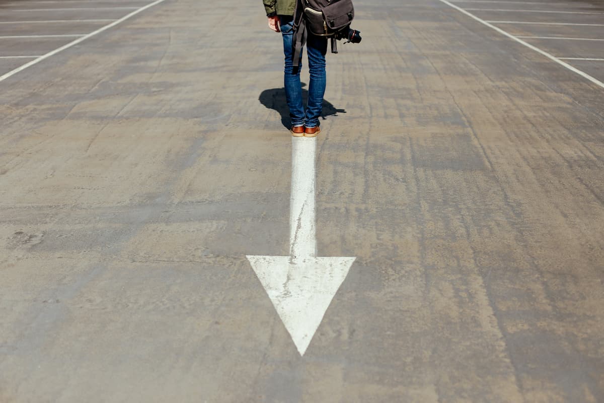 a woman standing on a street with an arrow. Understanding your past is not enough