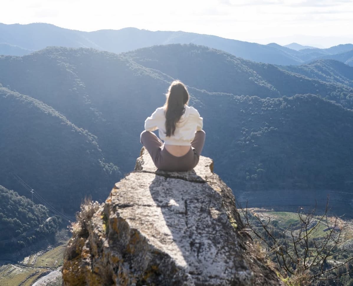 woman sitting on cliff after hiking finding herself again
