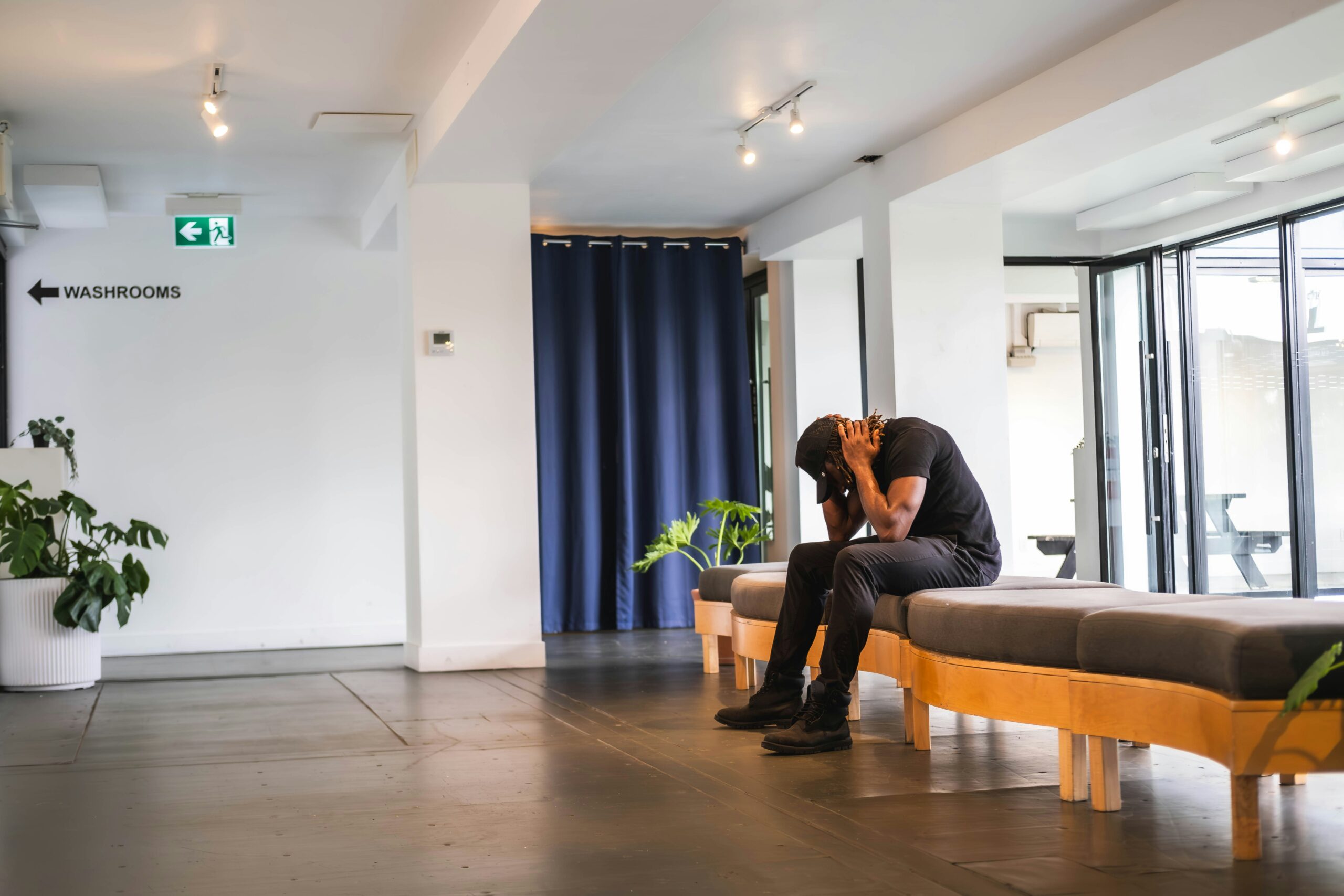 Man sitting on couch in a lobby with head in hands