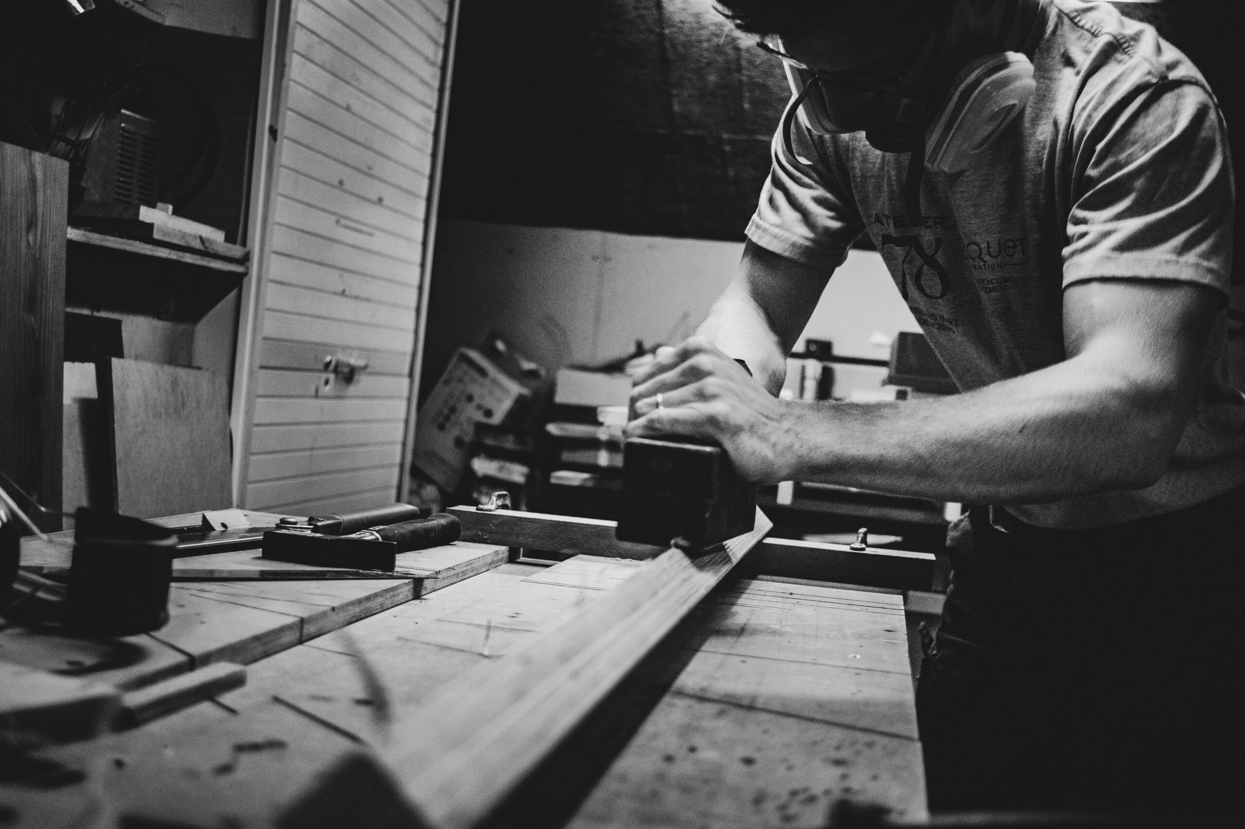 Woodworker smoothing a long plank of wood by hand at his workbench